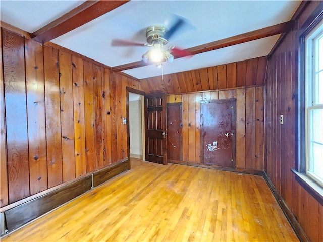 spare room featuring a wealth of natural light, wood-type flooring, and beam ceiling