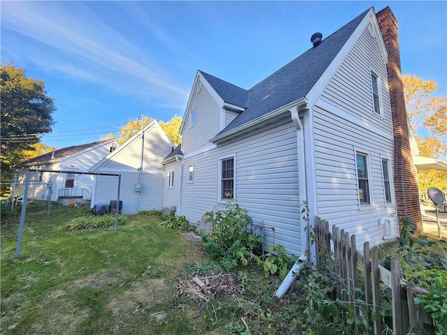 view of home's exterior with roof with shingles and a lawn