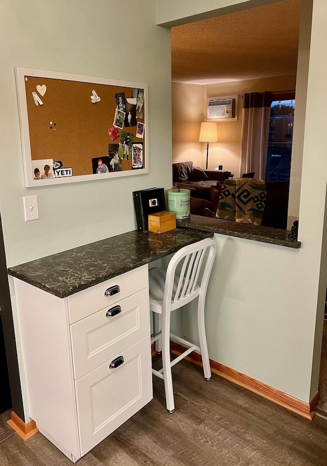 interior space featuring a wall mounted AC, dark stone counters, dark hardwood / wood-style flooring, a textured ceiling, and white cabinets