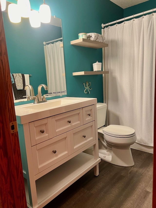 bathroom featuring toilet, hardwood / wood-style flooring, a textured ceiling, and vanity