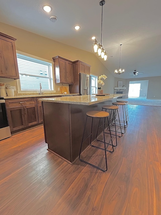 kitchen with vaulted ceiling, dark wood-type flooring, stainless steel appliances, and a center island