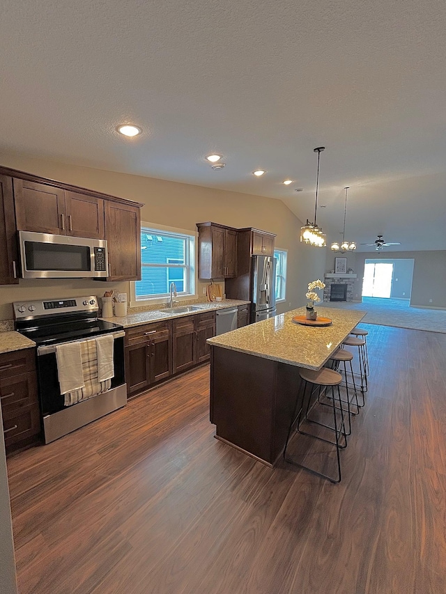 kitchen with lofted ceiling, a kitchen island, a kitchen bar, dark hardwood / wood-style flooring, and stainless steel appliances