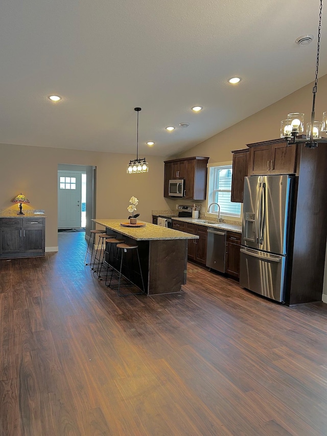 kitchen featuring decorative light fixtures, lofted ceiling, a center island, a kitchen bar, and stainless steel appliances