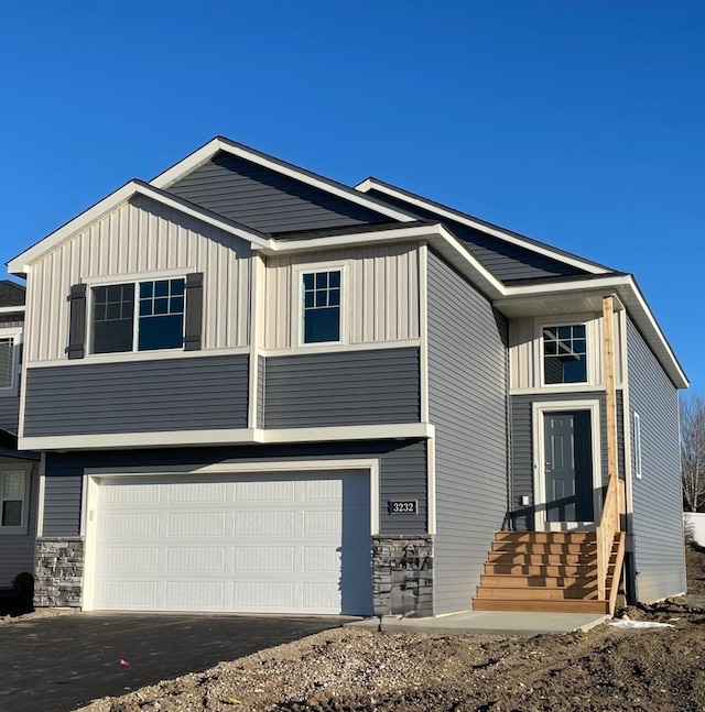 view of front of home with a garage, stone siding, board and batten siding, and driveway