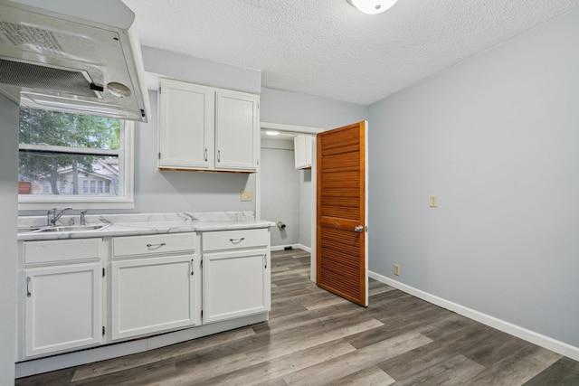 kitchen with sink, wood-type flooring, white cabinets, and a textured ceiling