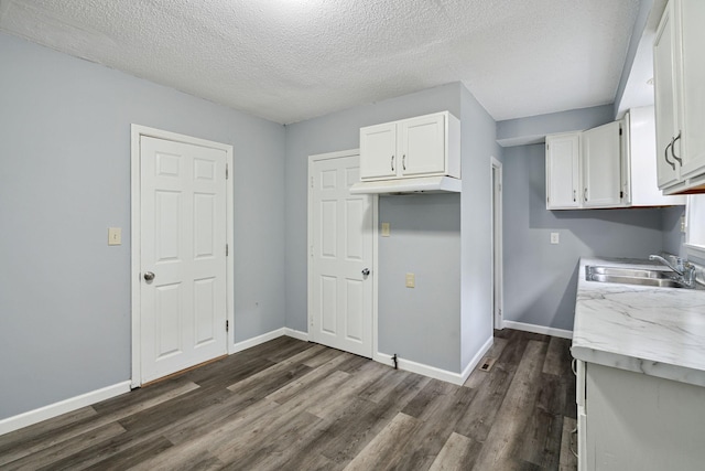 kitchen with white cabinets, a textured ceiling, dark wood-type flooring, and sink