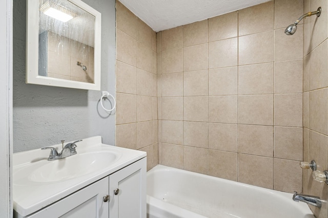 bathroom featuring a textured ceiling, vanity, and tiled shower / bath