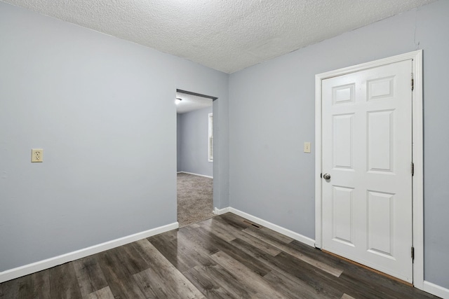 unfurnished room with dark hardwood / wood-style flooring and a textured ceiling