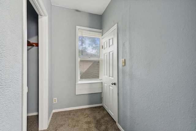 hallway featuring dark colored carpet