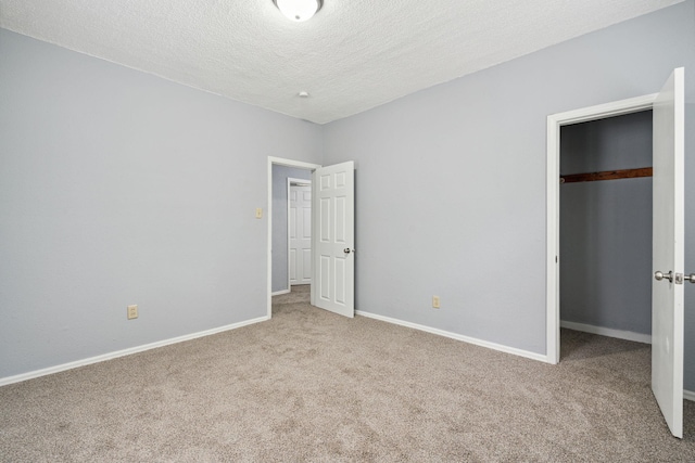 unfurnished bedroom featuring a textured ceiling, a closet, and light carpet