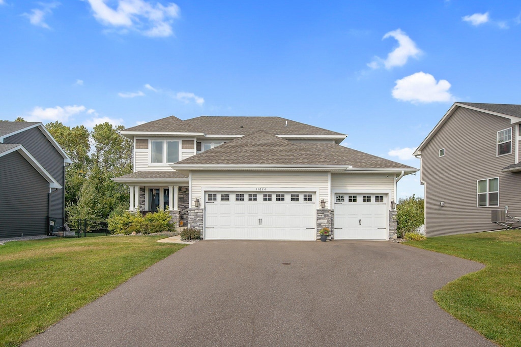 view of front of house featuring a garage, central air condition unit, and a front lawn