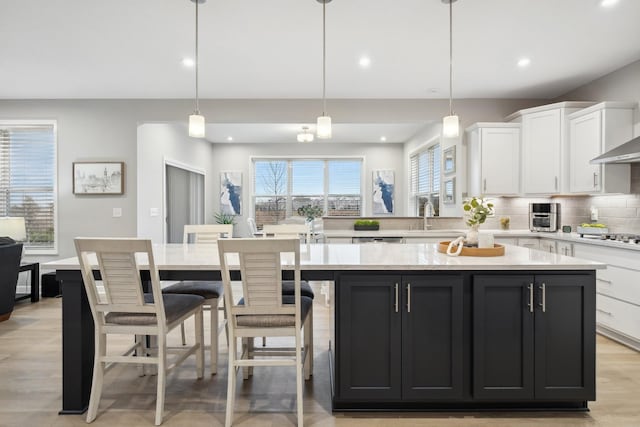 kitchen featuring white cabinetry, sink, a center island, and decorative light fixtures