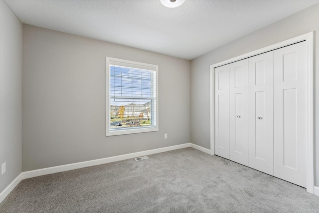 unfurnished bedroom featuring a closet and light carpet