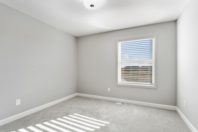 carpeted empty room with a textured ceiling