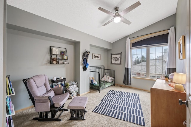 sitting room with ceiling fan, vaulted ceiling, carpet, and a textured ceiling