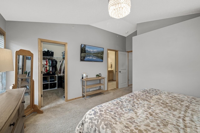 carpeted bedroom with ensuite bath, vaulted ceiling, a walk in closet, a closet, and a chandelier