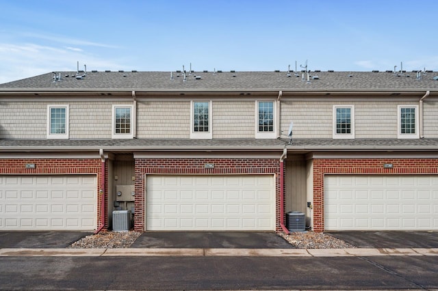 townhome / multi-family property with a garage and cooling unit