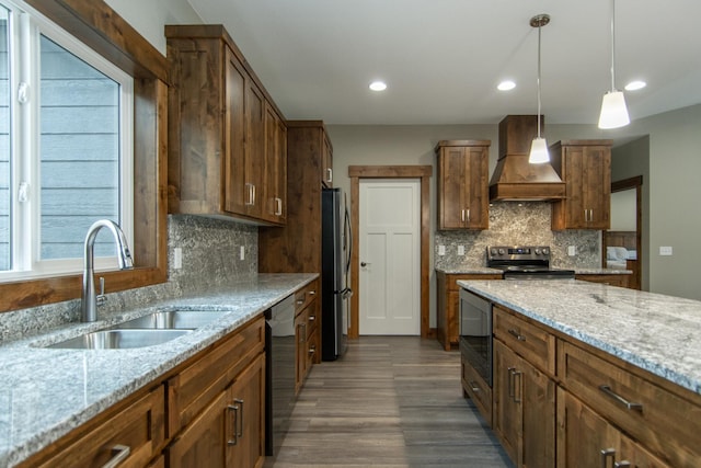 kitchen featuring sink, decorative light fixtures, light stone counters, custom range hood, and appliances with stainless steel finishes