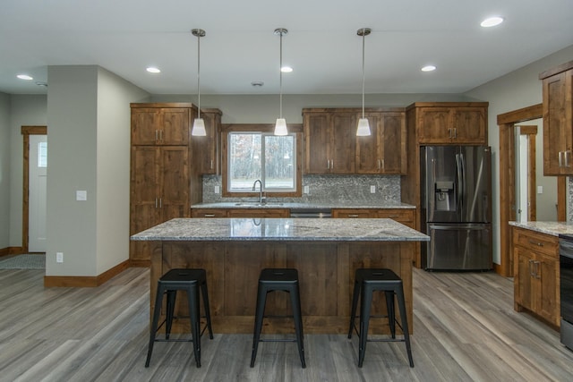 kitchen featuring a kitchen island, stainless steel appliances, and light stone countertops