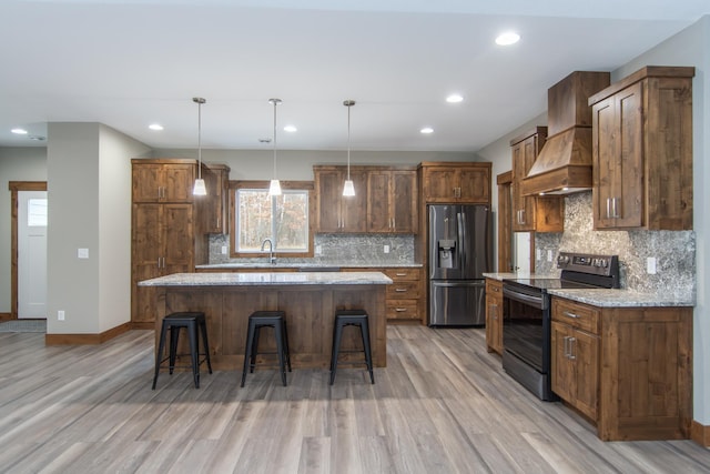 kitchen with light stone counters, premium range hood, stainless steel refrigerator with ice dispenser, a kitchen island, and electric range