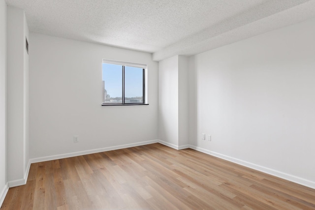 empty room with light hardwood / wood-style floors and a textured ceiling