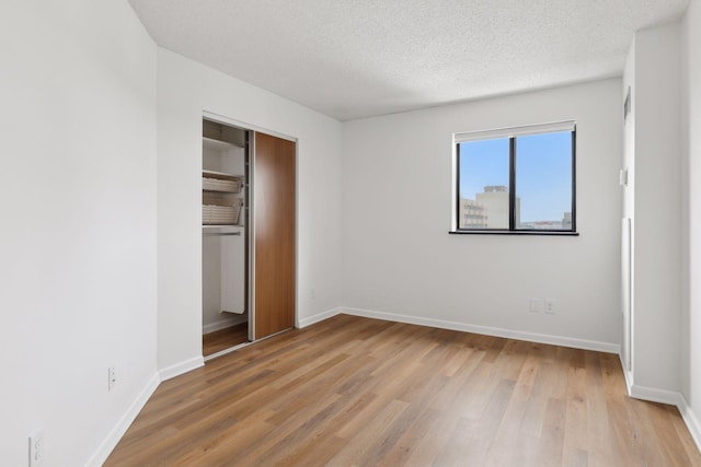 unfurnished bedroom featuring a textured ceiling, a closet, and light wood-type flooring