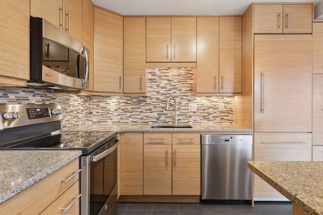 kitchen with light stone countertops, appliances with stainless steel finishes, dark tile patterned flooring, and tasteful backsplash