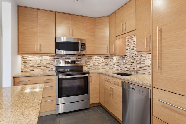 kitchen featuring stainless steel appliances, light stone counters, dark tile patterned flooring, and light brown cabinets