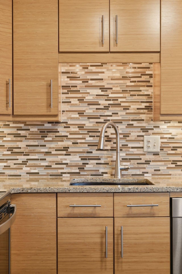 kitchen with decorative backsplash, sink, light stone counters, and light brown cabinets