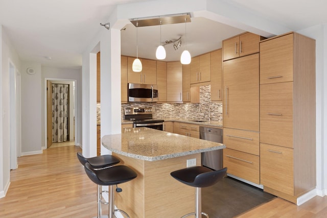 kitchen with pendant lighting, sink, appliances with stainless steel finishes, and light brown cabinets