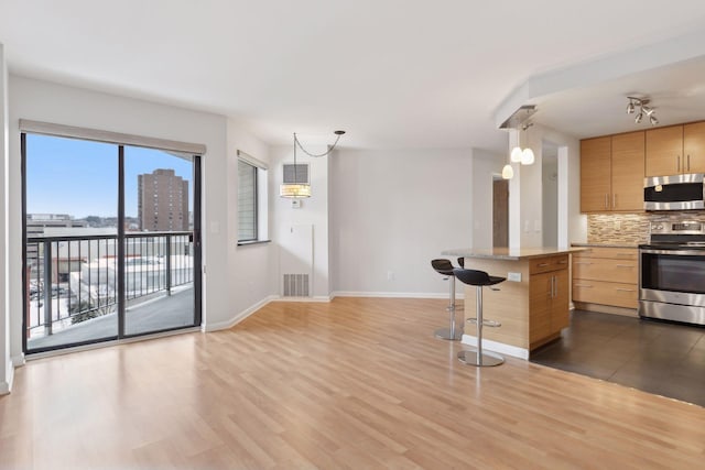 kitchen featuring pendant lighting, a breakfast bar, dark hardwood / wood-style floors, decorative backsplash, and stainless steel appliances