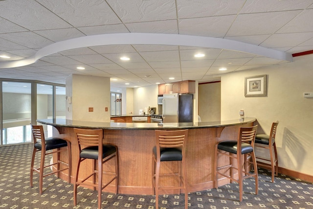 bar featuring dark carpet and stainless steel fridge