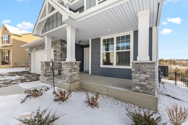 snow covered property featuring a garage, central AC, and a porch