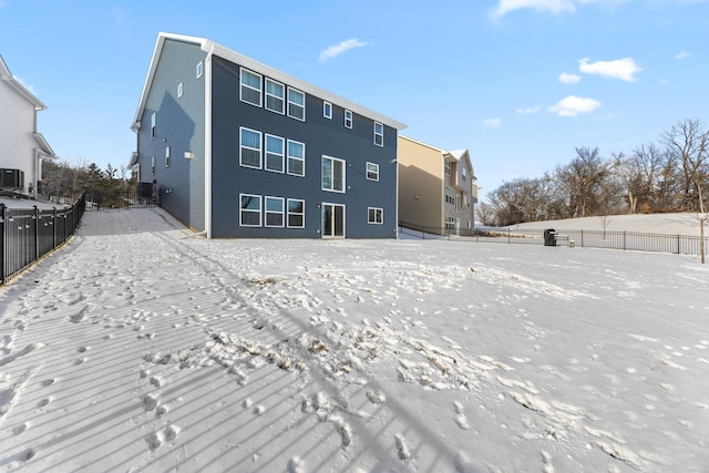 snow covered back of property featuring central AC unit