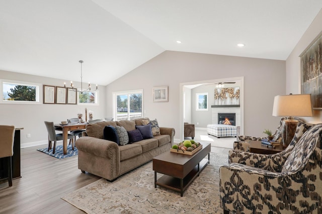 living room featuring light hardwood / wood-style floors, a notable chandelier, vaulted ceiling, and a fireplace