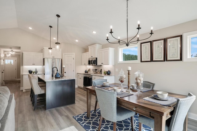 dining area featuring lofted ceiling, an inviting chandelier, and light wood-type flooring