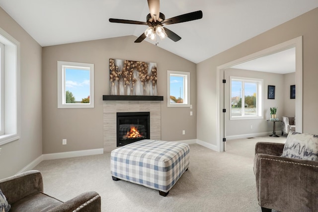 carpeted living room featuring ceiling fan, a tile fireplace, and lofted ceiling