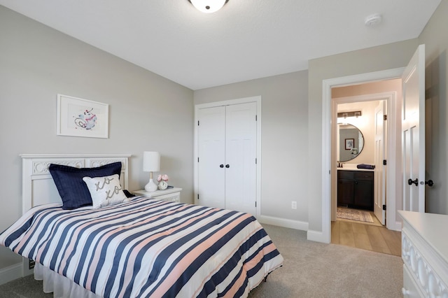 carpeted bedroom with ensuite bathroom and a closet