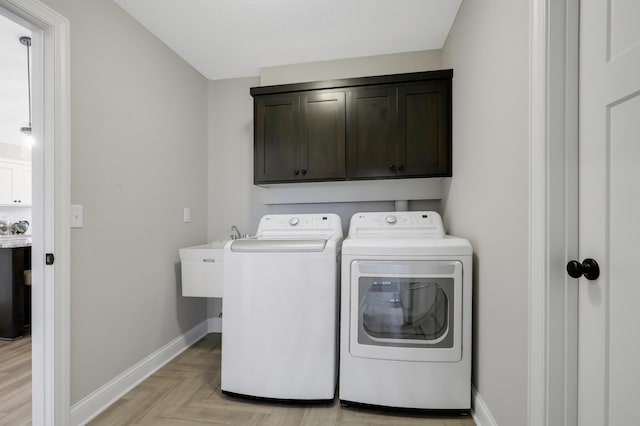 clothes washing area featuring sink, cabinets, independent washer and dryer, and light parquet flooring