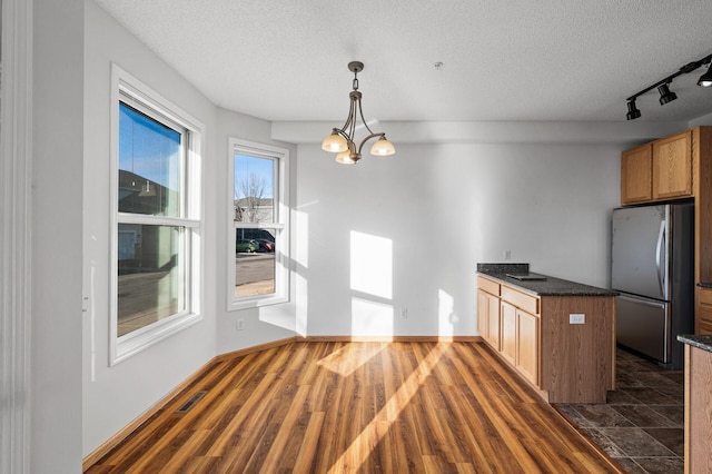 kitchen featuring pendant lighting, dark hardwood / wood-style flooring, stainless steel refrigerator, and a textured ceiling