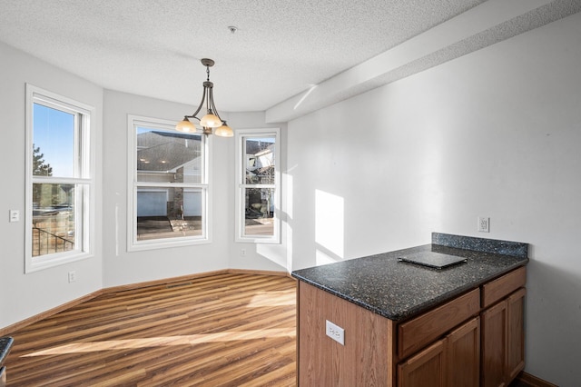 unfurnished dining area with a chandelier, light hardwood / wood-style flooring, and a textured ceiling