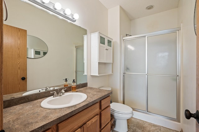 bathroom with tile patterned flooring, vanity, toilet, and a shower with shower door