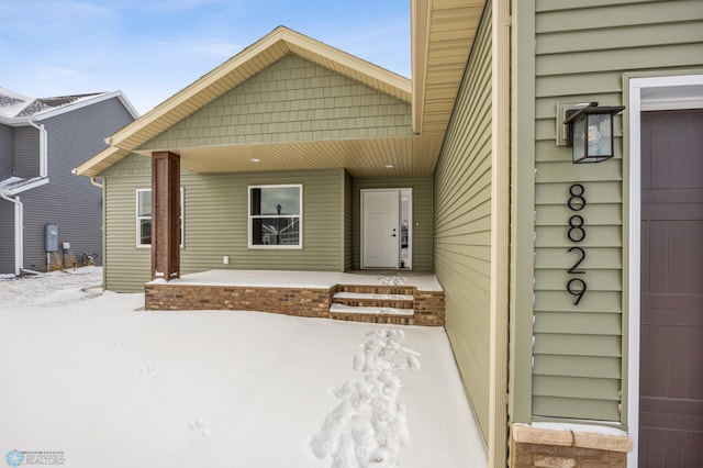 snow covered property entrance with a porch