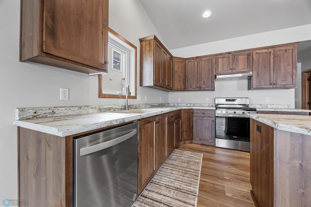 kitchen featuring light stone counters, sink, appliances with stainless steel finishes, and light wood-type flooring