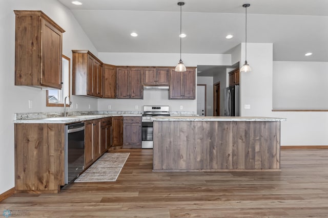 kitchen with pendant lighting, appliances with stainless steel finishes, a center island, and dark hardwood / wood-style flooring