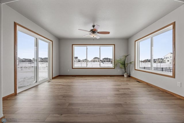 unfurnished room featuring ceiling fan, a healthy amount of sunlight, and light hardwood / wood-style flooring