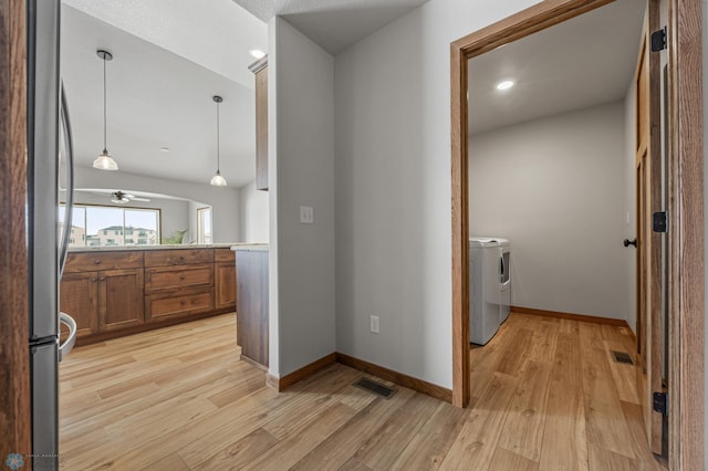 hall with light wood-type flooring and washing machine and clothes dryer