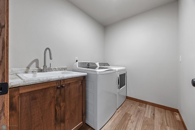 laundry room with light wood-type flooring, cabinets, independent washer and dryer, and sink