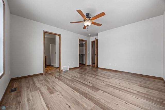 unfurnished bedroom featuring ceiling fan, a closet, light hardwood / wood-style flooring, and a walk in closet