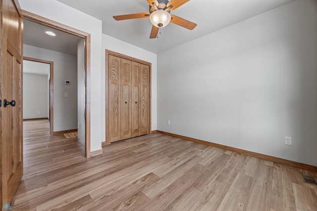 unfurnished bedroom featuring light wood-type flooring, ceiling fan, and a closet